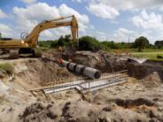 Backhoe installing concrete pipe at Southwest Lehigh Weirs