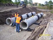 Two district employees installing two concrete culverts at Alden Street and Goldenrod Canal
