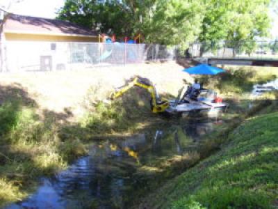 Truxor amphibious vehicle removing plants from the bank while inside the canal